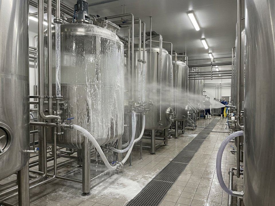 CIP cleaning system in operation inside a food processing facility with stainless steel tanks